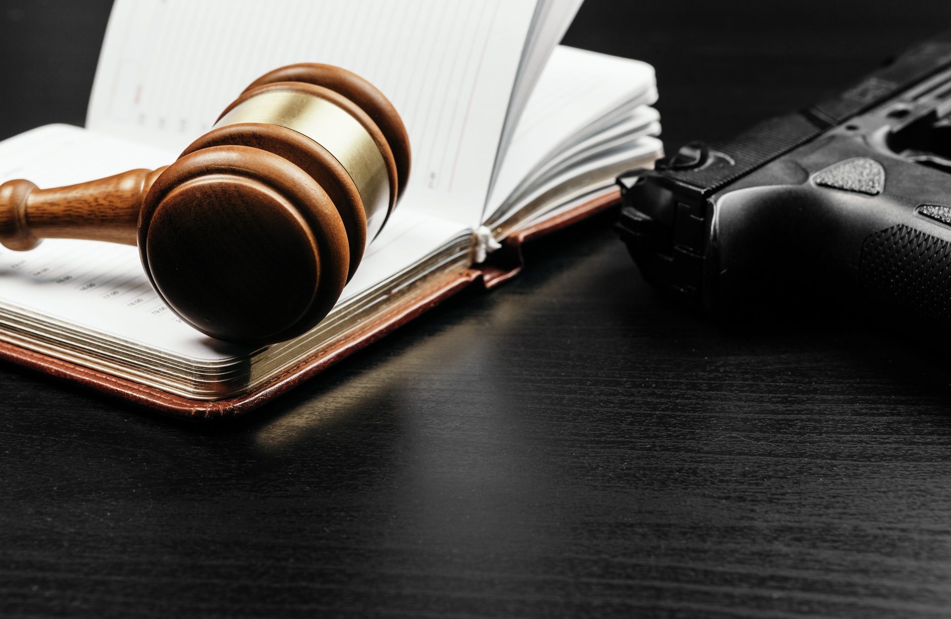 Abogados con experiencia en derecho penal en Almazora. Mallete encima de una libreta y junto a una pistola.