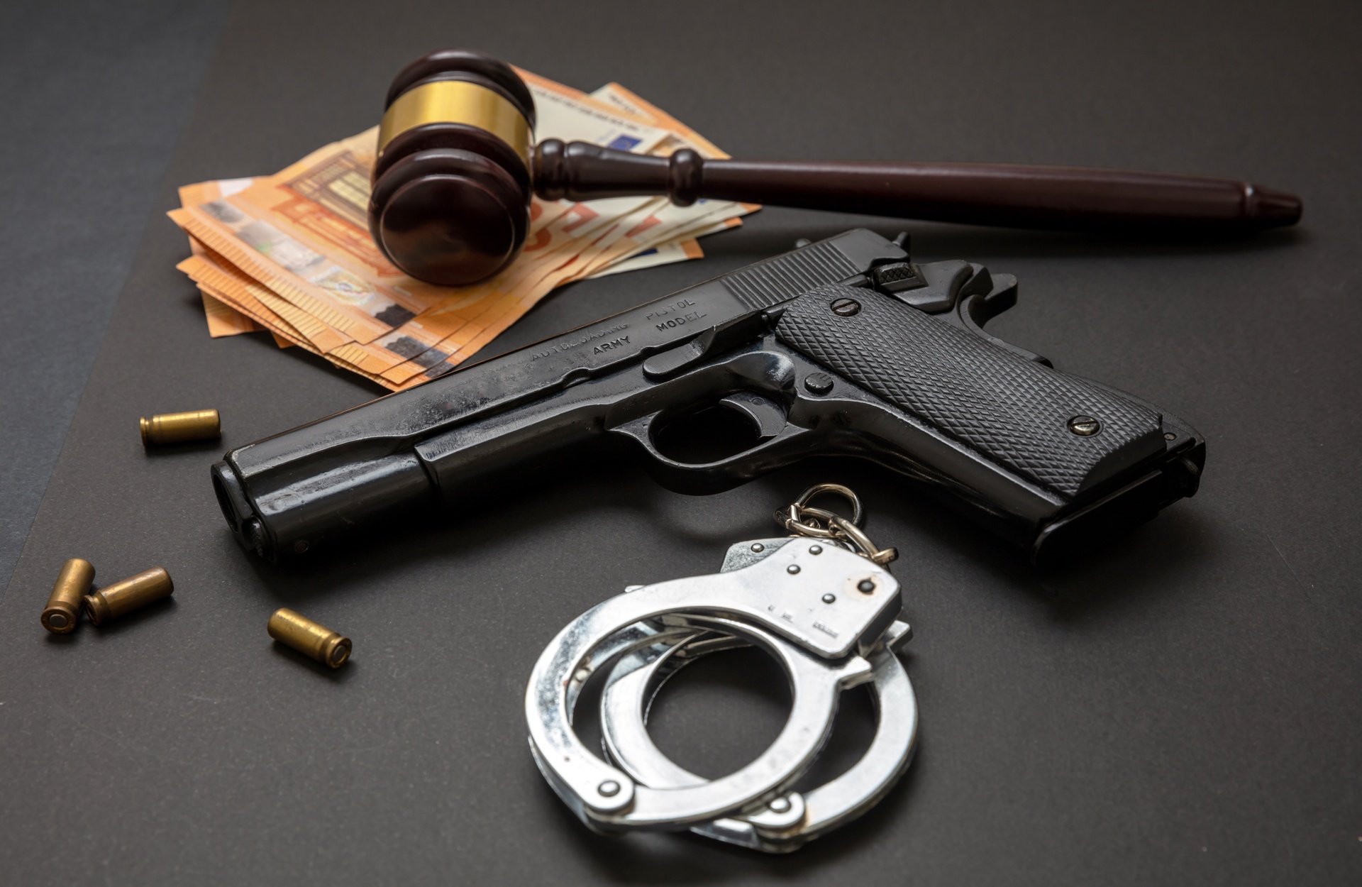 Capillartiga abogados, abogados enfocados en el derecho laboral en Burriana. Mallete junto a una pistola y unas esposas.