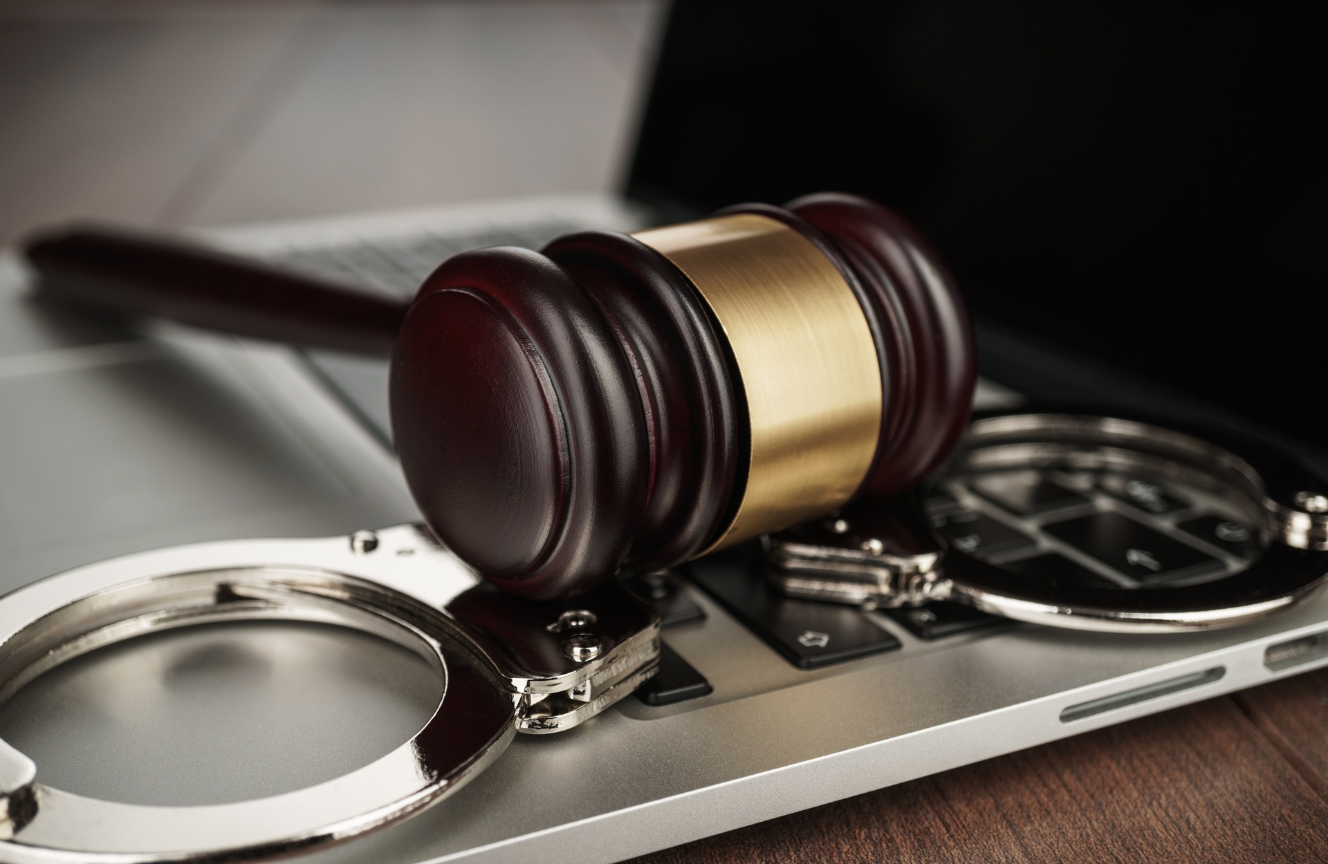 Capillartiga abogados, abogados expertos en derecho civil en El Grau de Borriana. Mallete sobre unas esposas y un portátil.