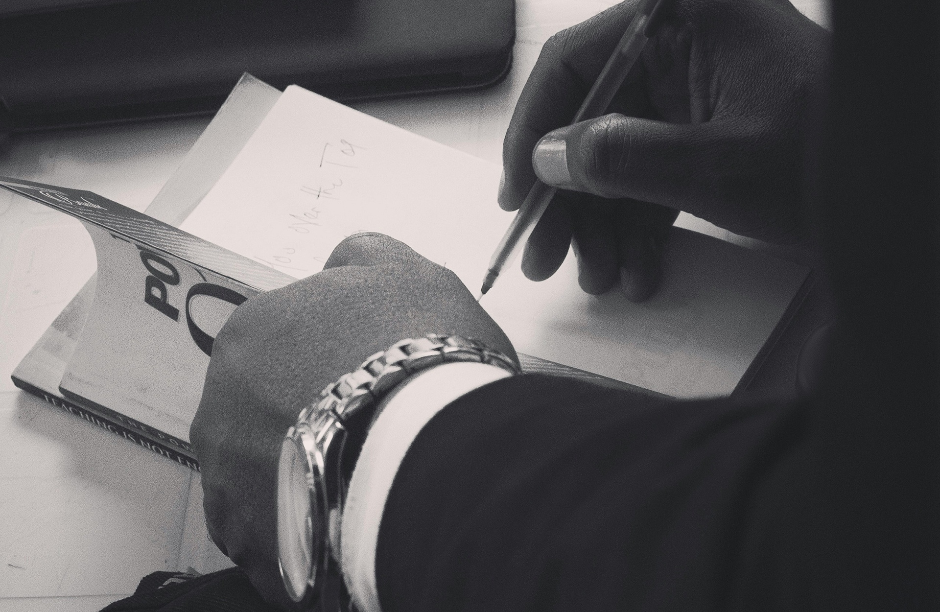 Capillartiga abogados, Derecho mercantil en Benicasim. Persona firmando unos documentos en blanco y negro.